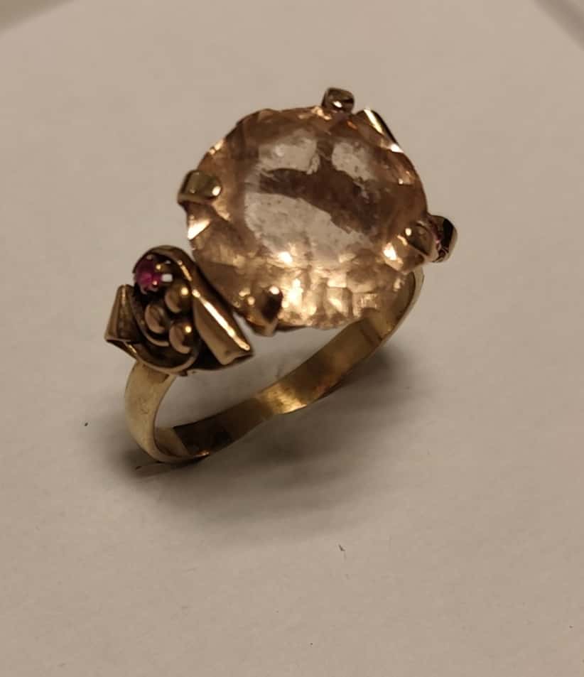UN ANILLO REALIZADO EN ORO KTE 18 CON VIDRIO CENTRAL (DESGASTES, ROTURAS) Y RUBIES SINTETICOS . (LAB INF 86527). PESO APROX. 5,2 GRS MEDIDA 22