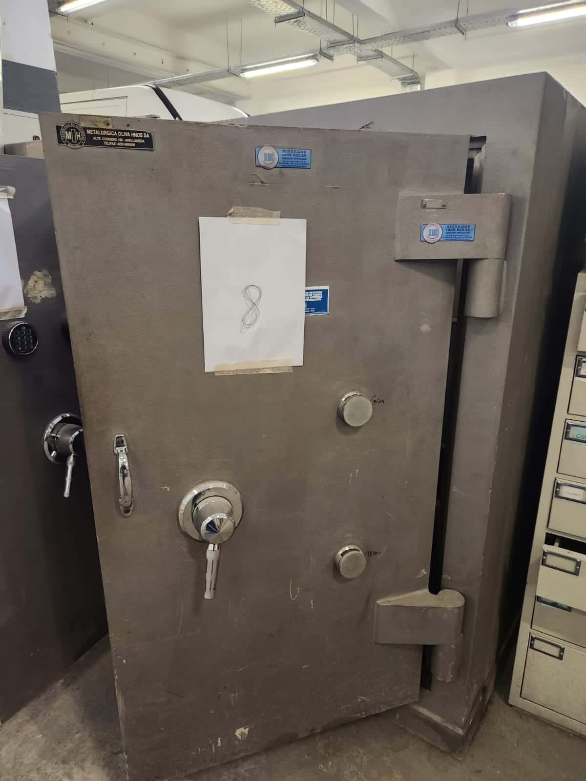 UN COFRE DE SEGURIDAD, USADO, MANUFACTURADO POR METALÚRGICA OLIVA HNOS S.A., IDENTIFICADO CON NÚMERO DE INVENTARIO 06209. CONSTRUIDO EN HORMIGÓN Y CHAPA DE ACERO, DIMENSIONES EXTERIORES APROXIMADAS: 1,80 M. DE ALTO POR 1,05 M. DE ANCHO Y 1.05 M. DE PROFUNDIDAD. PESO APROX. 3500 KG. T. POSEE UNA PUERTA FRONTAL CON BISAGRAS EXTERNAS REFORZADAS, SISTEMA DE CIERRE MECÁNICO CENTRAL TIPO VOLANTE Y DOBLE CERRADURA DE COMBINACIONES NUMÉRICAS. EN SU INTERIOR PRESENTA DOS COFRES SECUNDARIOS INDEPENDIENTES, CADA UNO CON CERRADURA DE COMBINACIÓN NUMÉRICA Y CERRADURA MECÁNICA, ESTANTE INFERIOR. CON DETERIOROS GENERALES, AVERÍAS, DESARMES E INCOMPLETO. SE VENDE EN EL ESTADO QUE SE ENCUENTRA Y EXHIBE.