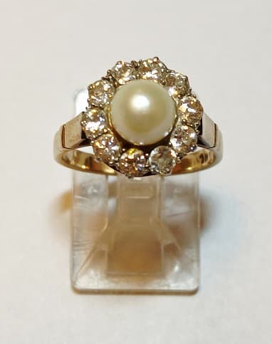 UN ANILLO DE ORO KTE 18, ADORNO DE PLATINO CON PERLA DE CULTIVO CENTRAL Y BRILLANTES CIRCUNDANTES QTE. 0.40 TOTAL APROX. (DEFECTOS). PESO 3 GRS. APROX. MEDIDA 9 APROX.