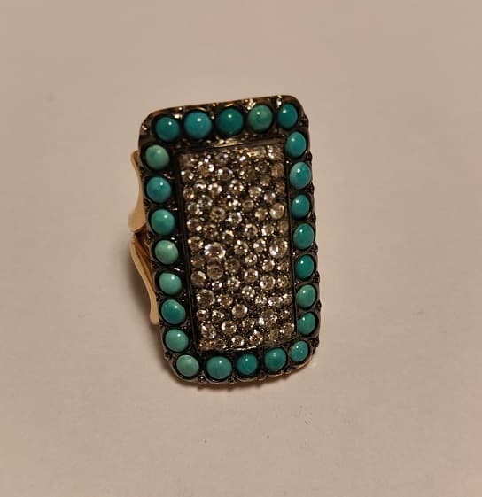 IMPORTANTE ANILLO REALIZADO EN ORO Y ORO BLANCO KTE 18 CON BRILLANTES QTE 0,90 TOTAL APROX. (DEFECTOS) Y VIDRIOS CELESTES (INF LAB 86348). PESO APROX. 19,1 GRS. MEDIDA 15. DETERIOROS EN GRAL.