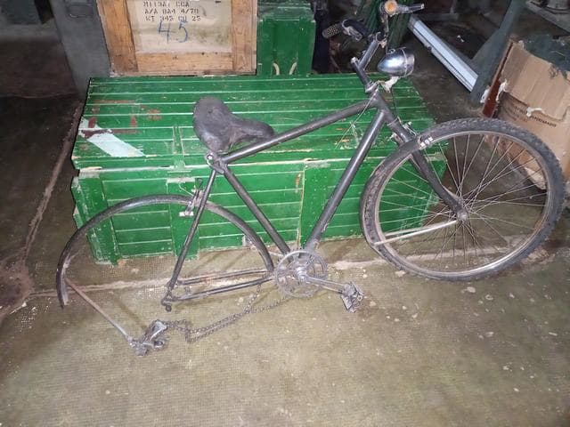 UNA BICICLETA, USADA, SIN MARCA VISIBLE. POSEE: MANUBRIO, ASIENTO, HORQUILLA, PEDALES, PLATO, CADENA Y UNA RUEDA ARMADA CON CUBIERTA DE MOVIMIENTO. CON DETERIOROS GENERALES, AVERÍAS, DESARMES Y MUY INCOMPLETA. S/NI