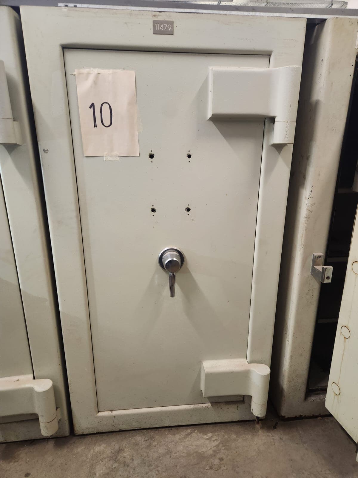 UN COFRE DE SEGURIDAD, USADO, SIN MARCA VISIBLE; IDENTIFICADO CON NÚMERO DE INVENTARIO 11479. CONSTRUIDO EN HORMIGÓN Y CHAPA DE ACERO, DIMENSIONES EXTERIORES APROXIMADAS: 1,85 M. DE ALTO POR 1,10 M. DE ANCHO Y 1.05 M. DE PROFUNDIDAD. PESO APROX. 3500 KG. POSEE UNA PUERTA FRONTAL CON BISAGRAS EXTERNAS REFORZADAS, SISTEMA DE CIERRE MECÁNICO CENTRAL TIPO VOLANTE, (SIN CERRADURAS DE COMBINACIÓN NUMÉRICA). EN SU INTERIOR PRESENTA DOS COFRES SECUNDARIOS INDEPENDIENTES, (SIN CERRADURAS MECÁNICAS NI COMBINACIÓN NUMÉRICA) Y ESTANTES INFERIORES. CON DETERIOROS GENERALES, AVERÍAS, DESARMES E INCOMPLETO. SE VENDE EN EL ESTADO QUE SE ENCUENTRA Y EXHIBE.