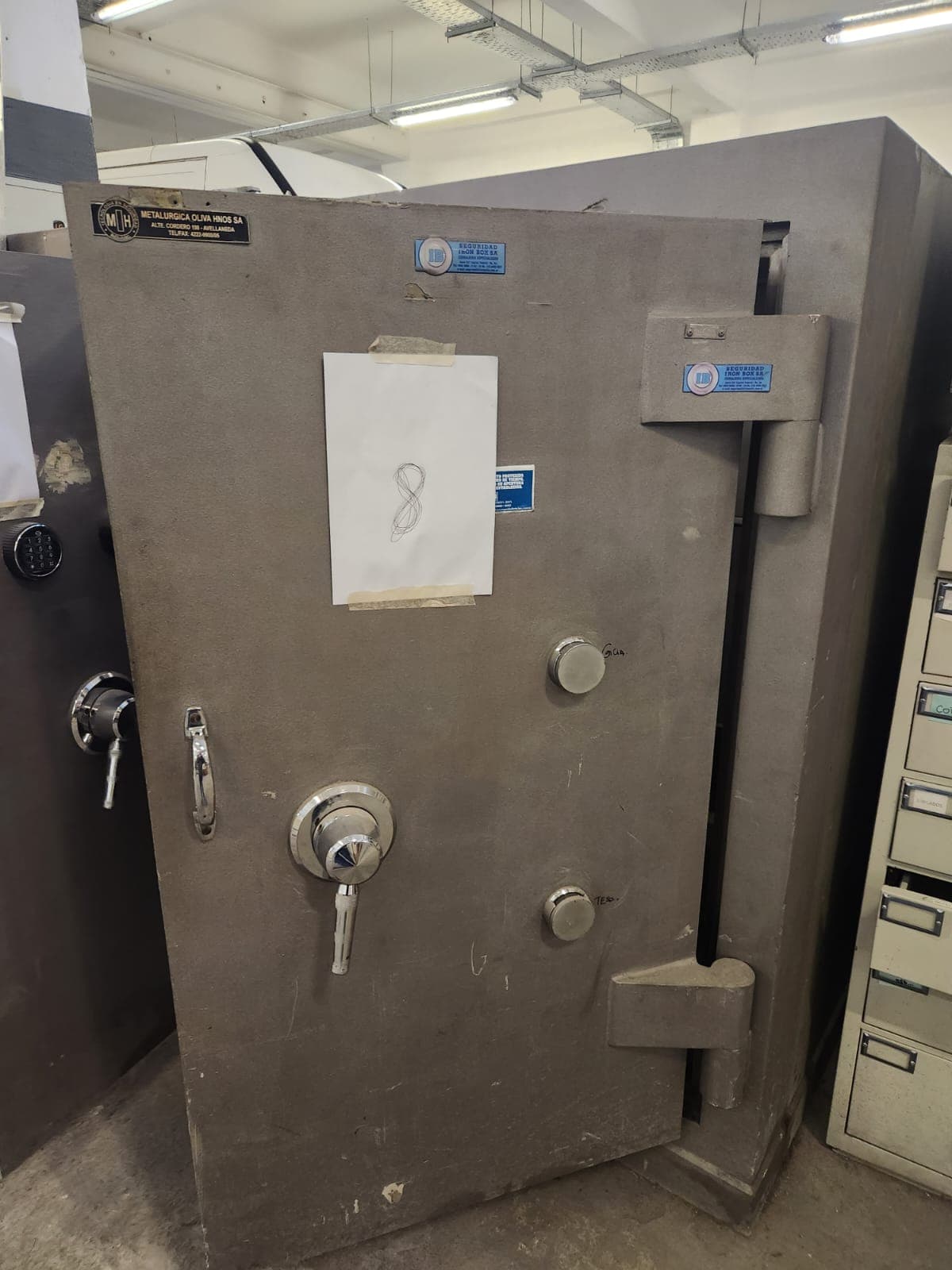 UN COFRE DE SEGURIDAD, USADO, MANUFACTURADO POR METALÚRGICA OLIVA HNOS S.A., IDENTIFICADO CON NÚMERO DE INVENTARIO 06209. CONSTRUIDO EN HORMIGÓN Y CHAPA DE ACERO, DIMENSIONES EXTERIORES APROXIMADAS: 1,80 M. DE ALTO POR 1,05 M. DE ANCHO Y 1.05 M. DE PROFUNDIDAD. PESO APROX. 3500 KG. T. POSEE UNA PUERTA FRONTAL CON BISAGRAS EXTERNAS REFORZADAS, SISTEMA DE CIERRE MECÁNICO CENTRAL TIPO VOLANTE Y DOBLE CERRADURA DE COMBINACIONES NUMÉRICAS. EN SU INTERIOR PRESENTA DOS COFRES SECUNDARIOS INDEPENDIENTES, CADA UNO CON CERRADURA DE COMBINACIÓN NUMÉRICA Y CERRADURA MECÁNICA, ESTANTE INFERIOR. CON DETERIOROS GENERALES, AVERÍAS, DESARMES E INCOMPLETO. SE VENDE EN EL ESTADO QUE SE ENCUENTRA Y EXHIBE.