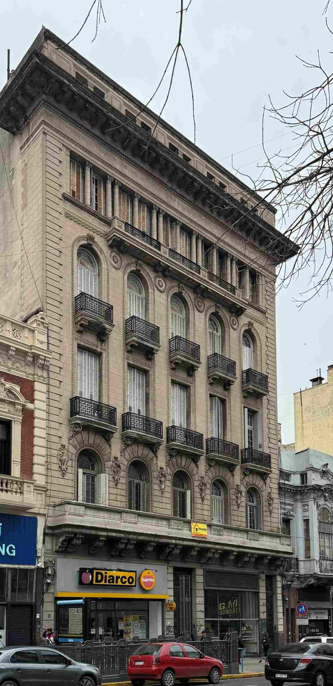 Sobre Av. Rivadavia 2446/60, piso 4 UF.12, CABA. En planta baja se ubica el acceso principal al edificio en el centro de la fachada, a cada lado se ubica un local comercial con acceso directo de la via pública. A la derecha del frente, sobre la medianera O, se ubica el otro acceso peatonal que vincula el frente con el primer piso directamente a traves de una escalera. La planta se organiza en torno a 2 núcleos de circulación vertical. El principal situado al centro próximo al acceso central, consta de un ascensor y escalera de escape circundante, desde el cual se accede a las 2 unidades que comparten el frente del edificio. El segundo núcleo de circulación se ubica sobre la medianera oeste hacia el sector medio posterior de la planta y vincula unidades entre el primer piso y el cuarto y acceso a la azotea. La ventilación e iluminación de las unidades se logra a traves de un patio de aire y luz central y de varios patios menores ubicados sobre las medianeras. La unidad se ubica en el piso 4, lado derecho de la planta, con frente hacia Av. Rivadavia, orientación Norte, ocupando hacia el contrafrente, compartiendo el piso con otras dos UF. Se accede a traves del palier de piso compartido con la UF 13 a un hall de distribución iluminado por una carpintería curva a traves de un vitreaux original, a partir del cual hacia el frente se ubica el living comedor de 9,85 m de ancho con 3 balcones a la calle. Hacia el contrafrente se ubican sucesivamente una serie de locales conformados por sala escritorio, comedor, baño, cocina, cinco dormitorios, alternados con 2 baños mas, terminando con un cuarto de trabajo. Todos los ambientes vinculados por una circulación iluminada naturalmente a traves de una Carpinteria de hierro con vidrio repartido, y a su vez ventilando a patios de aire y luz hacia la medianera este y al centro del lote en el tramo final. Entre el comedor y la cocina se accede por una escalera a un entrepiso en el cual se ubica una dependencia de servicio. Superficie: cubierta 360,95 m2, no cubierta balcón, superficie común de uso exclusivo 1,80 m2. Circunscripción: 10, Sección: 020, Manzana: 030, Parcela: 003A