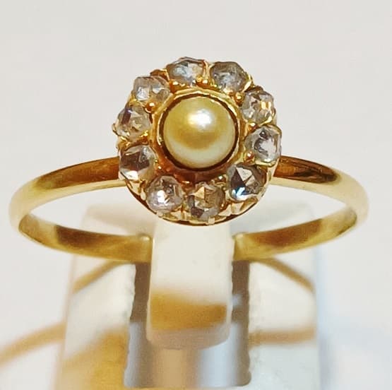 UN ANILLO REALIZADO EN ORO KTE 18 CON PERLA DE CULTIVO CENTRAL CON DIAMANTES CIRCUNDANTES PESO 2.1 GRS. MEDIDA 18
