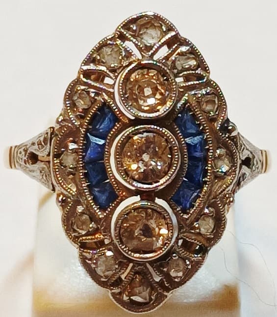 UN ANILLO REALIZADO EN ORO KTE 18 Y PLATINO CON BRILLANTES (DEF) QTE 0.25 TOTAL APROX., DIAMANTES COMPLEMENTARIOS CON PIEDRAS AZULES SIN POSIBILIDAD DE DETERMINAR. PESO APROX. 3.3 GRS. MEDIDA 16