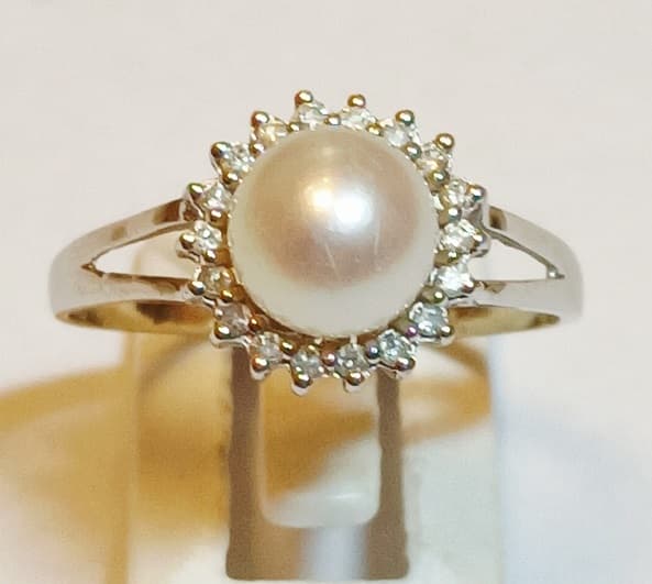 UN ANILLO REALIZADO EN ORO BLANCO BAJO KTE 14 CON PERLA DE CULTIVO CENTRAL Y BRILLANTES CIRCUNDANTES QTE 0.09 TOTAL APROX. PESO 2.3 GRS. APROX. MEDIDA 20